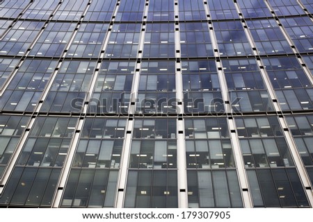the side of an office building made up entirely of windows to offices seen from below