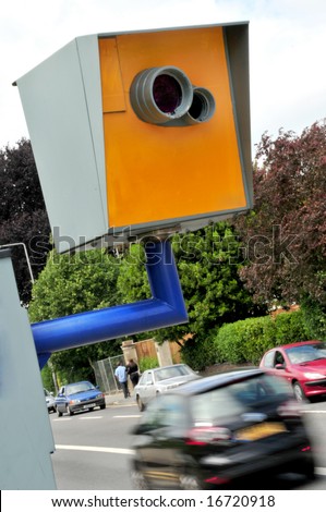 A Truvelo speed camera at the side of the road with blurred car passing