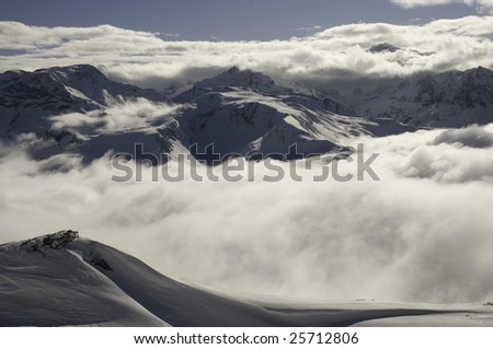 Low cloud in snow covered mountain valley, with low clouds surrounding distant mountains.