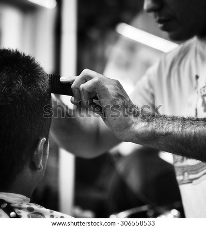 Deft Hands. At the barbers, detail of a handing holding a comb while cutting a clients hair.