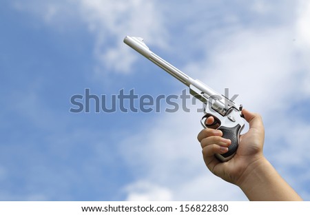 Gun in Hand on sky background