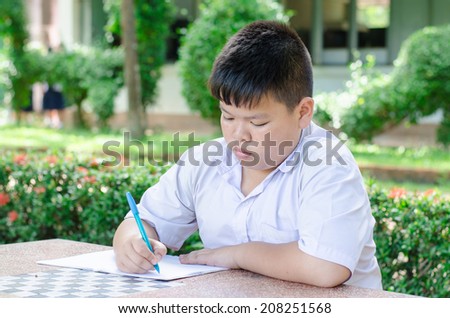 Male Student Working At Desk In  School.