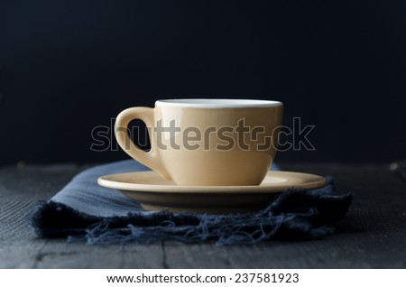 Coffee cup over dark blue cloth, dark and moody atmosphere