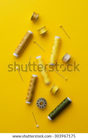 Colorful thread spools over bright yellow background, above view