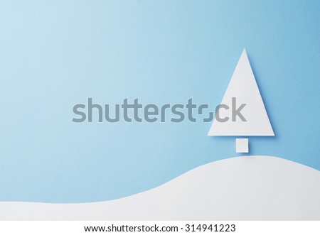 Paper christmas tree cut from white paper over blue background, top view