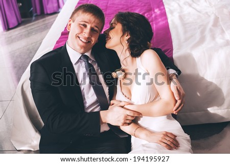 laughing bride and groom sitting near bed