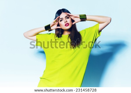 cute woman in neon green dress on blue background in studio