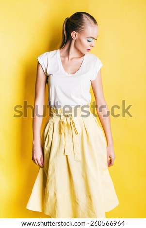 sensual woman in yellow skirt looking down on yellow background