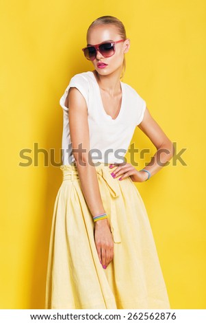 wet woman in pink sunglasses and yellow skirt on yellow background