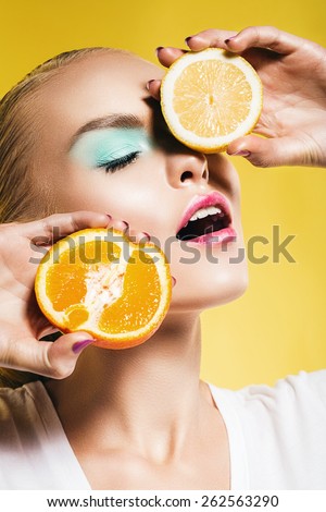 portrait of woman with lemon and orange on yellow background