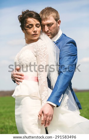 beautiful sensual married couple embracing on green field at sunny day