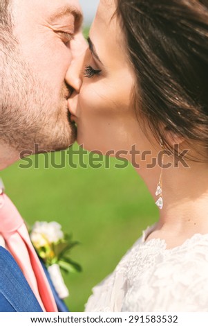 closeup portrait of kissing married couple on nature