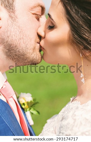 portrait of kissing married couple on green field at sunny day