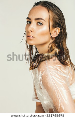 sexy woman in wet transparent top with snails in studio