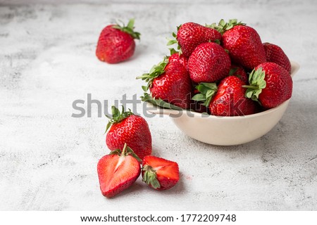 Fresh strawberries in a bowl on marble white table. Fresh nice strawberries. Strawberry field on fruit farm. Heap of Red strewberry on plate close up. Juice strawberry. Strawberry field on fruit farm.