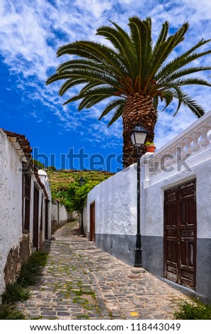 Street white house palm tree blue sky clouds canary style, Los Silos town, Tenerife