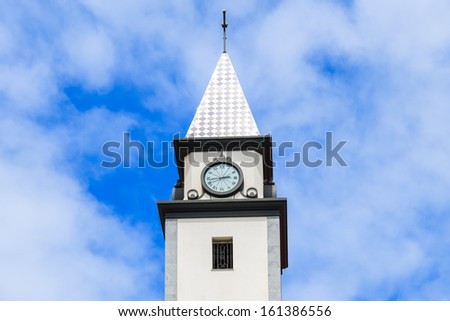 White church tower in small Portuguese town and sunny sky with white clouds, Madeira island, Portugal