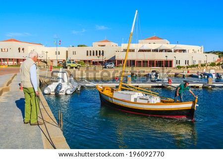PORTO GIUNCO PORT, SARDINIA - MAY 27, 2014: fishing boat returns from open sea to Porto Giunco port. Many fishermen anchor boats here and sell fresh fish to restaurants in the harbour.