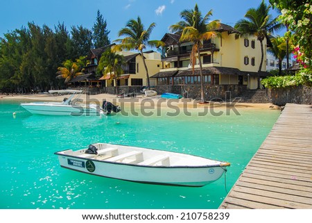 GRAND BAIE BEACH, MAURITIUS ISLAND - SEP 19, 2010:  boats and holiday houses on paradise tropical beach in Grand Baie coastal village. Many people visit Mauritius island each year to catch winter sun.