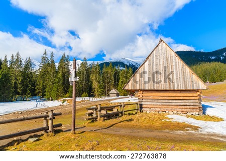 Wooden hut and mountain trail sign in Chocholowska valley in spring season, Tatra Mountains, Poland