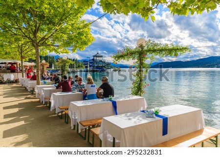 WORTHERSEE LAKE, AUSTRIA - JUN 20, 2015: people sitting at tables along Worthersee lake shore during summer beer festival.