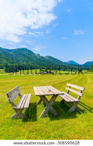 Wooden benches with table on green meadow in summer landscape of Alps Mountains, Weissensee lake, Austria
