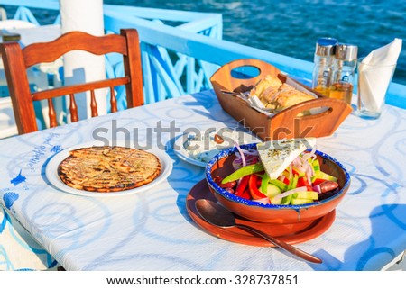 SAMOS ISLAND, GREECE - SEP 20, 2015: Greek salad on table in traditional tavern with blue sea water in background on Samos island, Greece
