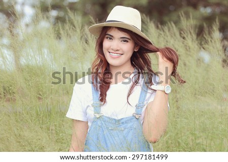 Cheerful multiracial Asian woman wearing a hat in the grassland, red soft tone