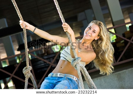 Cute blond girl swinging on rope swings