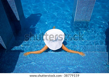 Girl in white hat sitting in the swimming pool