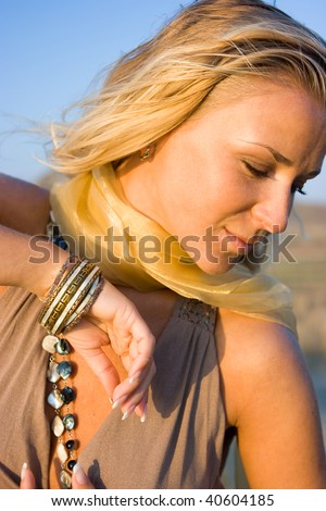 Close-up portrait of a young blonde woman with bracelet on hand