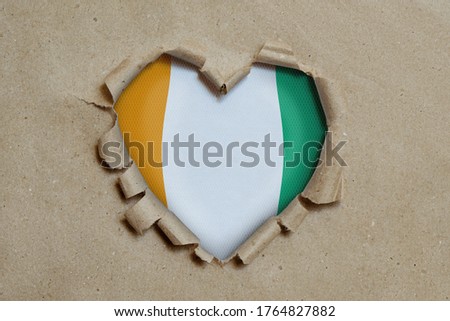 3d illustration. Heart shaped hole torn through paper, showing Cote d'ivoire flag Stock fotó © 