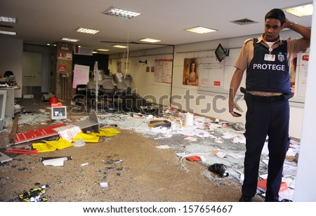 RIO DE JANEIRO, BRAZIL - OCTOBER 8: A private security agent observes a vandalized bank agency at Rio de Janeiro's downtown on the day after the schoolteachers demonstrations demanding better wages on October 8th, 2013 in Rio de Janeiro, Brazil.