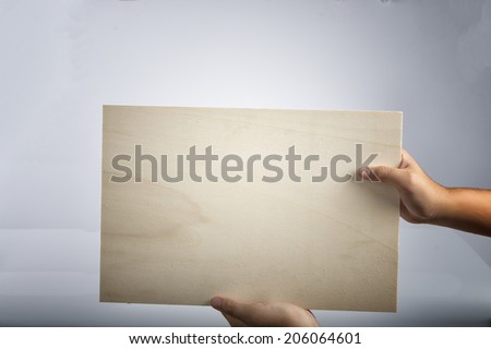 Young caucasian hands holding a light plywood  square blank signboard isolated on white background. There are no elements to distract viewer from reading any  message written on the sign