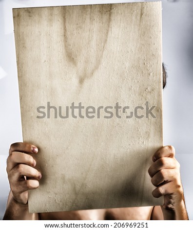 Young caucasian boy holding a dramatic light color plywood square blank signboard with hands. His face is covered and there are no elements to distract viewer from reading the message on the sign