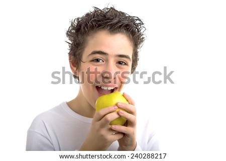 A handsome Caucasian boy wearing a long sleeved white shirt is goingt to bite and eat a yellow apple with both hands