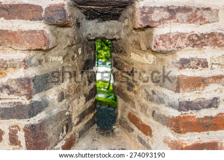 Vertical narrow medieval window in an ancient brick wall in Prague on country landscape.  View from the Basilica of St Peter and St Paul in Vysehrad