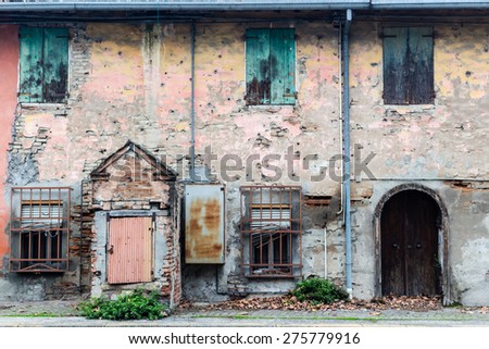 Rusty windows and doors in ruined wall of an old farmhouse in countryside in Emilia Romagna in Italy