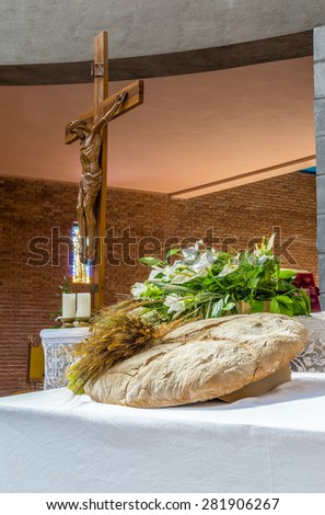 bread, grapes and ears of wheat as a symbol of Christian Holy Communion in Italian Catholic Church. Wood statue of the crucifixion of Jesus Christ in the background