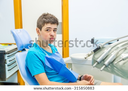teenager sitting in the chair of the dentist and calmly waiting for the medical dentist while blowing cheeks