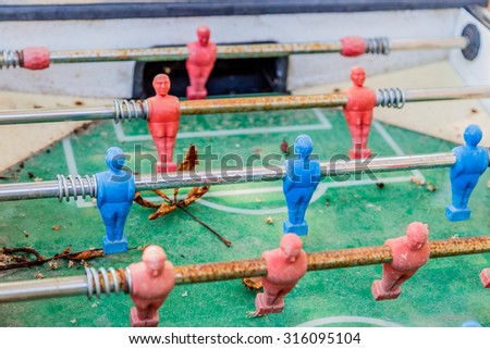 details of red and blue table football dummy players, dirty and rusty, covered with leaves and dust