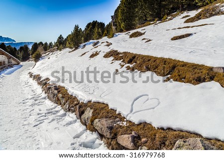 love sentences written in the snow with green conifers in the background on Dolomites Alps: I miss you, hugs and kisses, heart