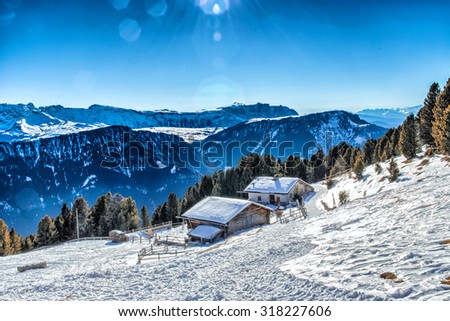 panorama of the Dolomites with wood cottage,  snow-capped peaks and green conifers