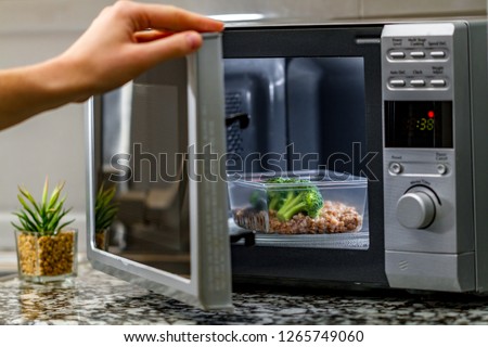 Using the microwave oven to heat food. Heating plastic container with broccoli and buckwheat in the microwave