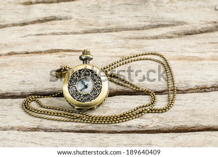 Ancient pocket watch and necklace isolated on old wooden  background.