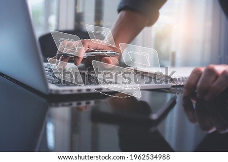 E-document, paperless office concept. Businessman working on laptop computer keyboard with electronics document icons on virtual screen