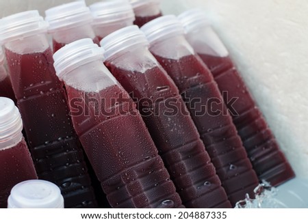 Bottles of mulberry juice cooling in ice.