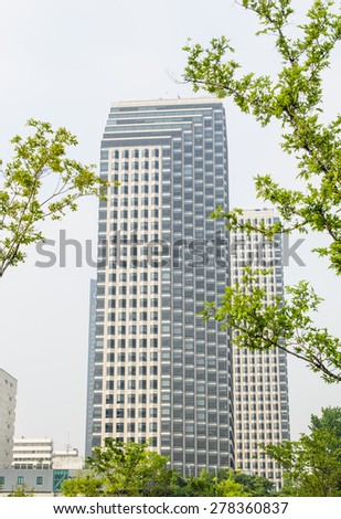Tall office building in the city, tree foreground.