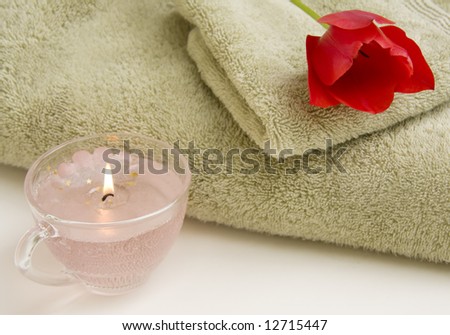 Still life of towel, hand cloth, candle and red tulip.