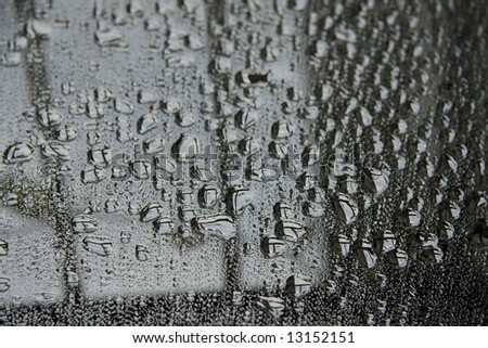 Water droplets and a mirror reflect a porch rail.